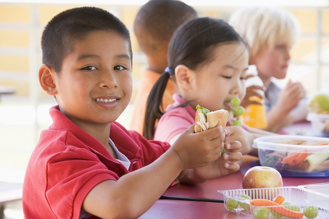 Kindergarten children eating packed lunch together